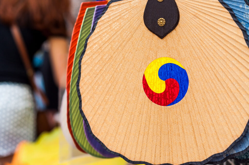 a fan painted with a traditional korean symbol