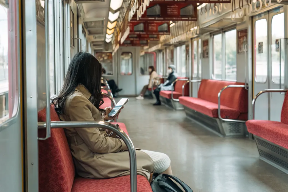 An international student sitting inside a clean Seoul subway train car, using Seoul public transportation.